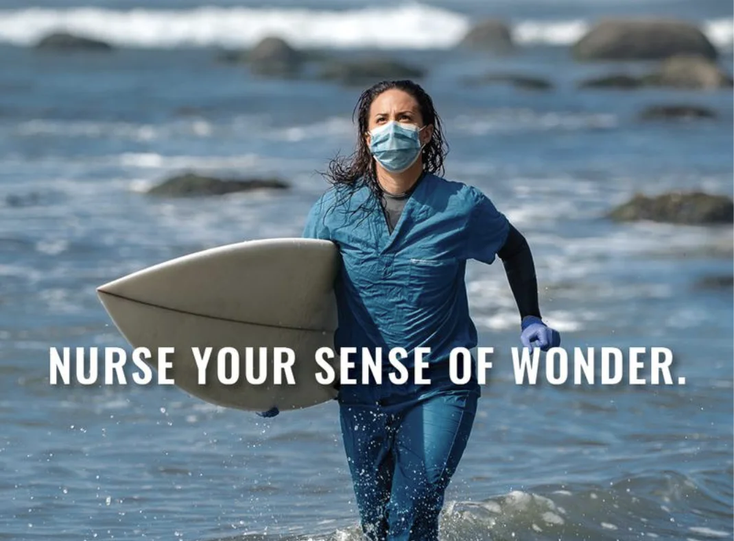 Nurse Your Sense of Wonder, a nurse in a mask and scrubs running into the ocean with a surfboard